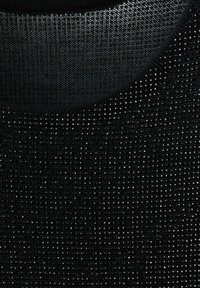 Maglione nero con superficie testurizzata e piccoli dettagli lucidi. Il collo è rotondo ed è realizzato con materiale liscio a contrasto.