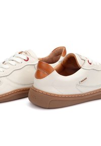Zapatillas de cuero blanco con detalles en marrón, puntera redonda, cierre de cordones en la parte delantera y suela acolchada. Presenta ojales rojos y costuras visibles.