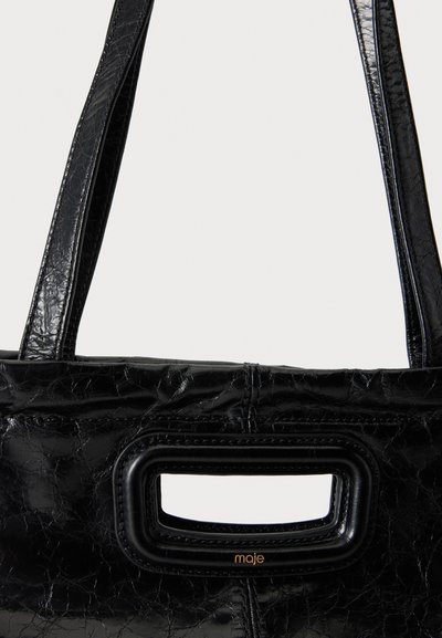 Sac à main en cuir noir texturé avec double bandoulière et une poignée rectangulaire découpée, avec un petit logo doré "maje" sous la poignée.