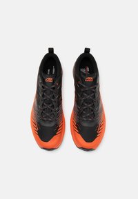 Sorte og orange atletik sko med en let mesh-overdel, tekstureret design og forstærket tåområde. Har en polstret sål og snørebånd.