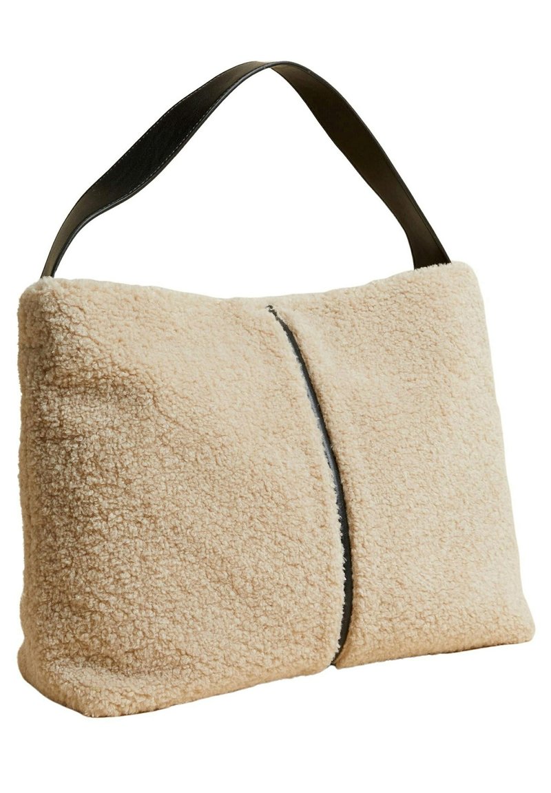 Beige skuldertaske i tekstureret imiteret pels med sort læderrem; rektangulær form med en central sømdetalje langs forsiden.
