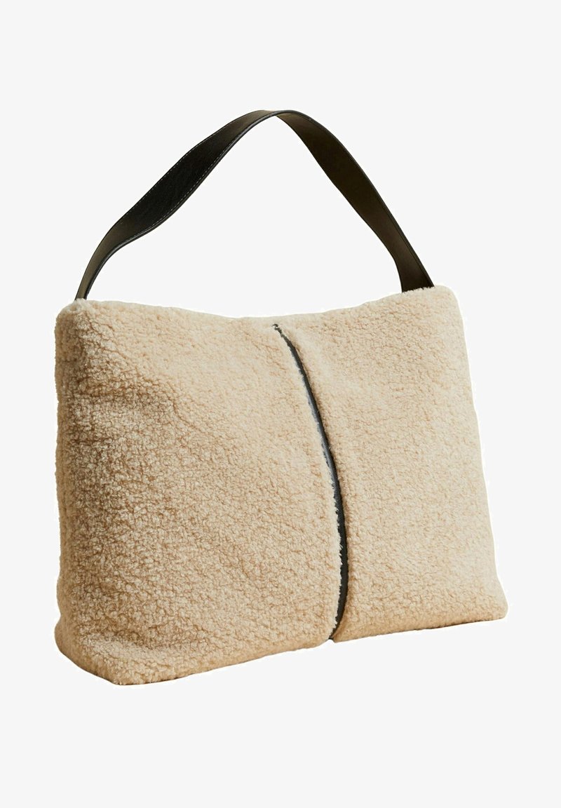 Beige skuldertaske i tekstureret imiteret pels med sort læderrem; rektangulær form med en central sømdetalje langs forsiden.