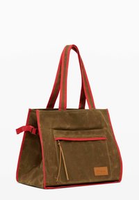 Brown canvas tote bag with red trim, featuring two sturdy handles, a front zip pocket, and a leather logo patch.