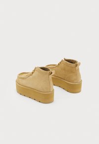 Bežīgi zamšādas potītes zābaki ar noapaļotu purngalu, auklu dizainu un biezu gumijas zoli ar teksturētu apakšu, lai nodrošinātu saķeri.