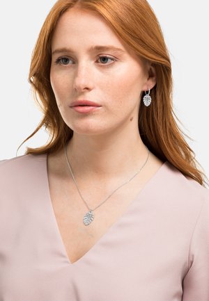 Silbernes Schmuckset mit einer blattförmigen Anhänger-Halskette und passenden Ohrringen, die mit filigranen Details auf einer strukturierten Oberfläche verziert sind.