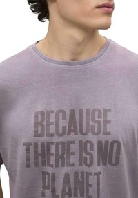 Camiseta de algodón lavanda clara con cuello redondo, que presenta un texto en negrita negro: "PORQUE NO HAY PLANETA" a lo largo del pecho.