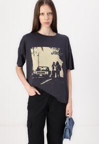 Čierne grafické tričko vyrobené z bavlny, na prednej strane s potlačou vintage auta a dvoch postáv v béžovej farbe. Voľný strih a krátke rukávy.