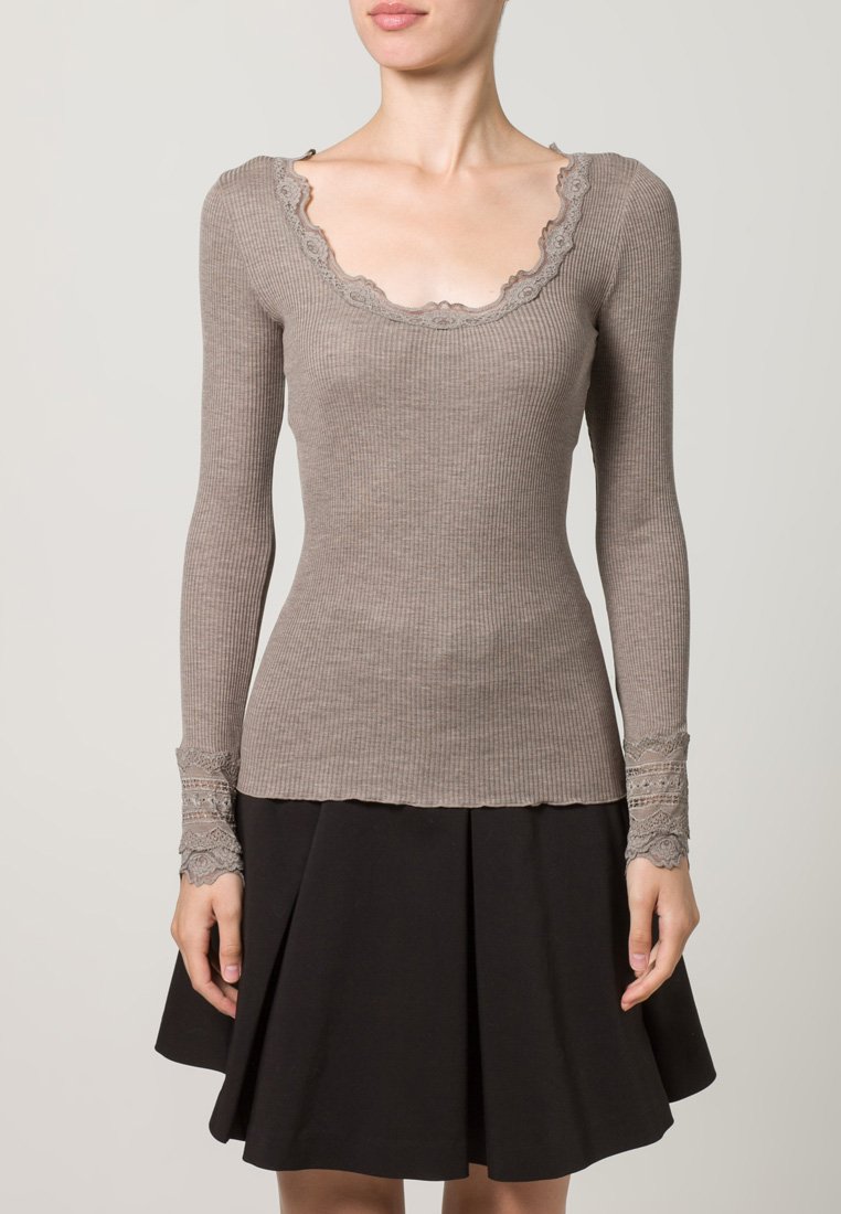 Rebrasti top dugih rukava u tofi boji s valovitim izrezom i čipkom na rukavima; uparen s crnom suknjom na zvono.