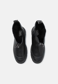 Bottines noires en cuir avec panneaux latéraux élastiques, bout rond et semelle en caoutchouc. Comprend un logo sur la tirette du talon et un intérieur texturé.