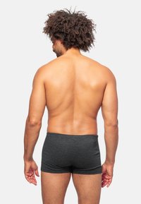 Boxer shorts noirs à rayures, en tissu doux, design ajusté, longueur mi-cuisse, avec une taille élastique. Le dos nu du modèle est visible.