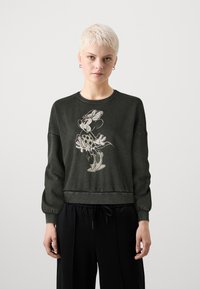 Sötétzöld pulóver, kerek nyakkivágással és hosszú, enyhén puffos ujjal. Fényes szürke színű grafika egy mesefiguráról.