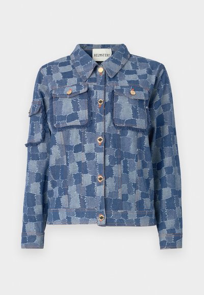 Casaco de ganga com um padrão em patchwork azul, botões prateados e dois bolsos frontais. O material tem um acabamento texturizado e bordas desfiadas.