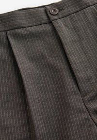 Gray pinstriped trousers with a flat front, featuring a brown button, discreet stitching, and a smooth texture. Includes side pockets.