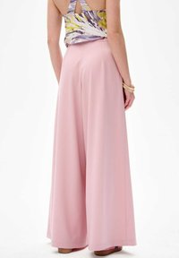 Lichtroze wijde broek van flowy materiaal met een gladde textuur, met een middelhoog taille en zijzakken.