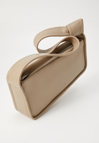Borsa rettangolare beige in pelle liscia con chiusura a zip e manico curvo annodato sulla parte superiore. Design minimalista con un marchio discreto.