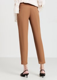 Braune maßgeschneiderte Hosen mit schmaler Passform und glatter Textur. Mit Gesäßtaschen und Knöchellänge, kombiniert mit sandalen mit Riemchen und Absatz.