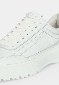 Baskets blanches en cuir avec semelle épaisse, lacets blancs et marquage discret "CPH" sur le côté et la languette.