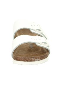 Sandalo in stile Birkenstock bianco con due cinghie regolabili, una soletta testurizzata e una suola in sughero marrone. Materiale superiore in plastica liscia.
