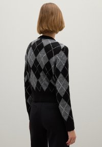 Zwart en grijs ruitpatronen sweater met een cropped ontwerp, lange mouwen en geribde zoom, gemaakt van zachte, gestructureerde stof.