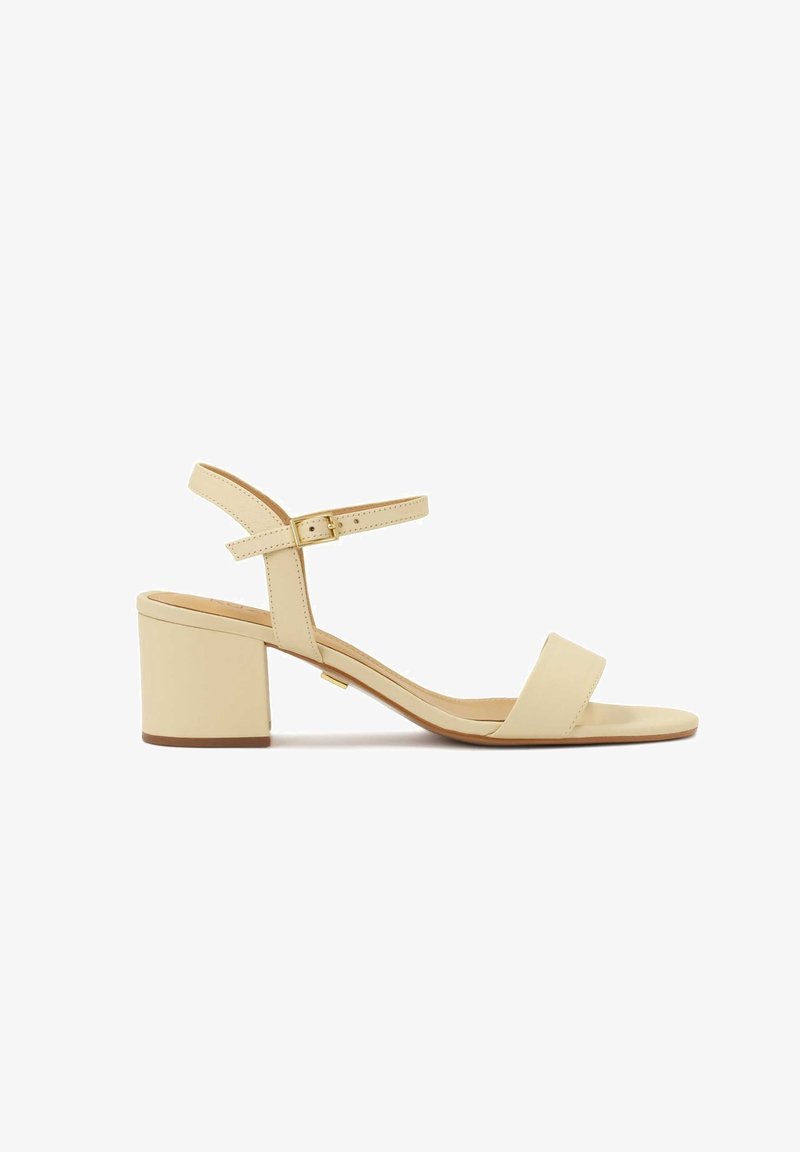 Sandale beige à bout ouvert avec un talon bloc et une bride de cheville réglable avec une petite boucle dorée.