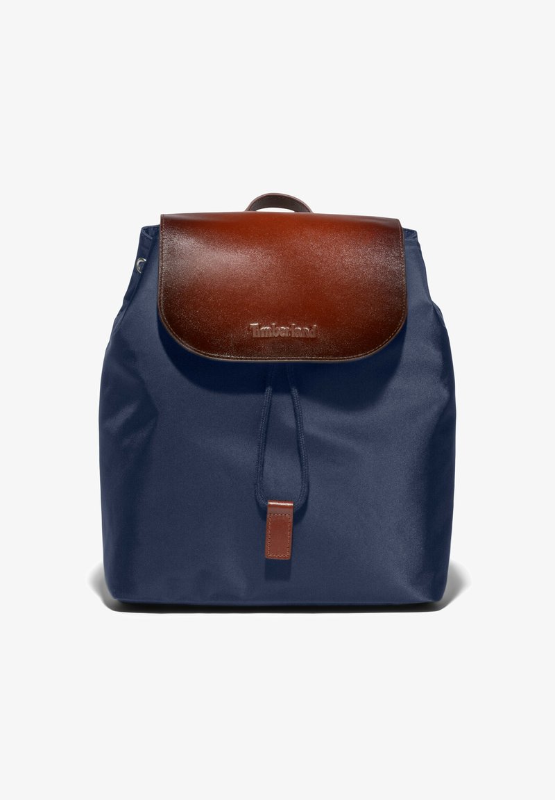 Sac à dos bleu marine avec rabat en cuir marron et fermeture à cordon, avec le logo Timberland sur le rabat avant.