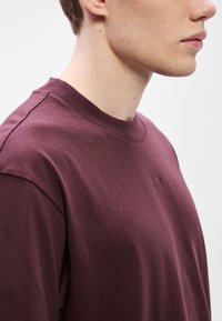 Bordo majica z okroglim izrezom iz bombaža, z rokavi do komolcev, gladke teksture in z diskretnim reliefnim logotipom spredaj.