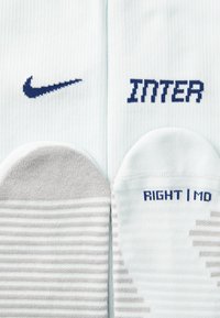 Nike čarape u svijetloplavoj boji, s tamnoplavim logom i natpisom "INTER". Jedna čarapa je siva s bijelim prugama; oznake za "DESNA" i "MD."