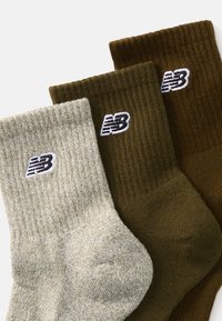 Kolm paari ribast sokki: üks heledashall, üks tume roheline, üks pruun, igaühel on varre peal väike valge New Balance'i logo.