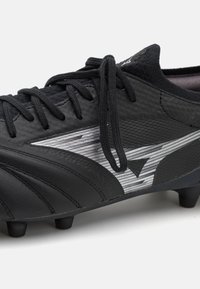 Black soccer cleat featuring a textured leather upper, black laces, and a metallic silver stripe design. Angled toe and molded studs.