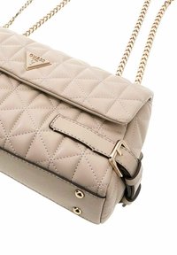 Sac à main beige matelassé avec bandoulière chaîne dorée, logo triangulaire et détail boucle ; présente un motif de losanges cousus et une texture lisse.