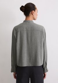 Gray, textured long-sleeve shirt with a turned-down collar, dropped shoulders, and buttoned cuff accents. Shows back view and cropped length.