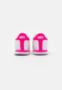 Asics-skor i vitt, rosa och orange. Funktionerna inkluderar en slät ovandel, vadderad krage och logotyp på hälen, med en svart gummisula.