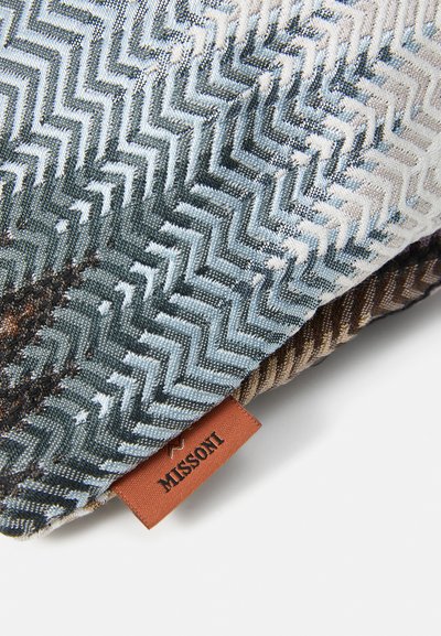 Close-up of folded chevron-patterned fabric in blue and brown shades with a brown Missoni brand label attached.
