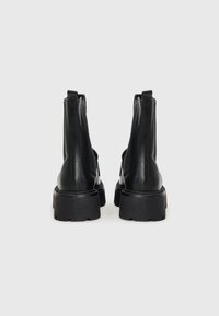 Black leather ankle boots with a smooth texture, rounded toe shape, elastic side panels, and thick rubber lug sole.