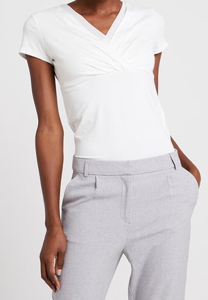 Witte korte mouwtop met een overslagontwerp bij de halslijn, gecombineerd met grijze, op maat gemaakte broek met zijzakken en een gladde textuur.