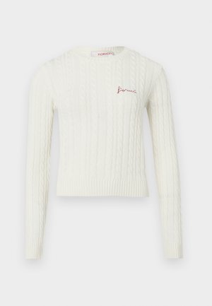 Pull en ivoire tricoté avec un design en câble texturé, coupe courte, manches longues et un petit logo rouge brodé sur la poitrine.