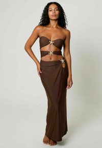 Brun tvådelad outfit med ett strapless topp med tvinnat tyg och sjöstjärneförzinkningar, ihop med en lång, åtsittande kjol med utskärningar.