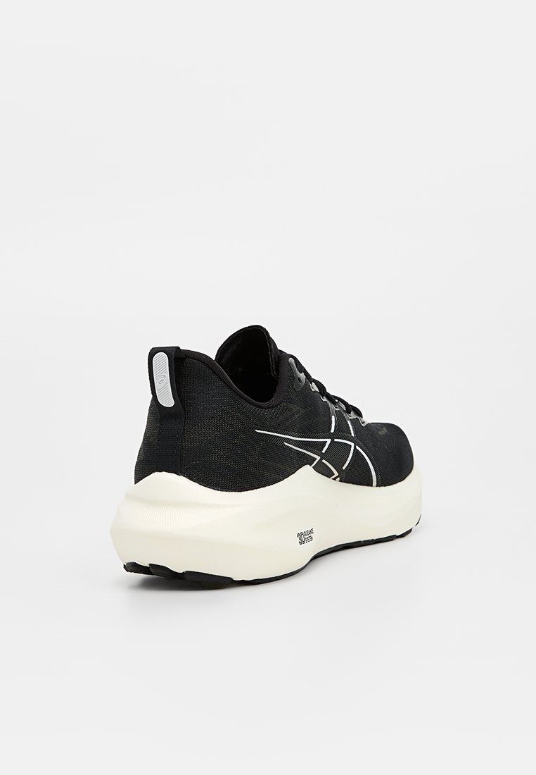 Zwart sportieve schoen met een gestructureerde bovenkant, witte accenten, een dikke crèmekleurige tussenzool en een versterkte hielcap. Opvallend lichtgewicht ontwerp.