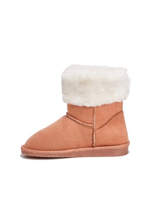Tan suède enkelboots met een fluffy witte schapenvachtkraag, ronde neus en gestikte details langs de naden en de basis.