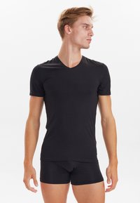 Black v-neck t-shirt made of soft fabric, fitted design, short sleeves, paired with black boxer shorts. Smooth texture, minimal detailing.