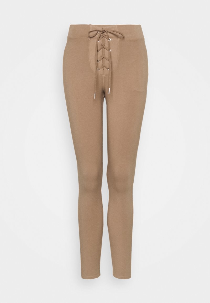 Ljusbruna leggings med en åtsittande design, med en snörning fram, elastisk midja och mjuk textur.