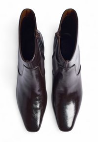 Rjavi usnjeni gležnjarji z sijočo površino, z ostrim nosom, stranskim zadrgo in preprosto ukrivljeno obliko. Gladka tekstura brez vidnih vzorcev.