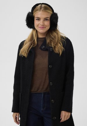 Cappotto di lana nera con finitura testurizzata, caratterizzato da grandi bottoni neri e tasche laterali, abbinato a paraorecchie in pelliccia nera. Top marrone sotto.