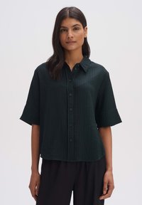 Dark green, short-sleeve button-up shirt with a textured, ribbed pattern. Features a collar and matching buttons, loose fit design.