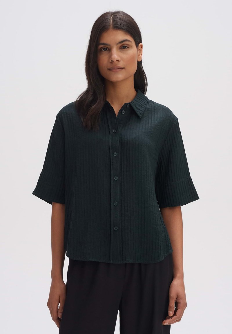 Dark green, short-sleeve button-up shirt with a textured, ribbed pattern. Features a collar and matching buttons, loose fit design.
