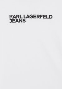Camiseta de algodón blanca con texto negro en negrita: "KARL LAGERFELD JEANS" en el pecho. Diseño simple sin gráficos adicionales.