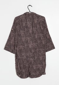 Brun mönstrad kimono med korta ärmar, som har en löst sittande design och ett subtilt leopardmönster. Hänger på en svart krok.