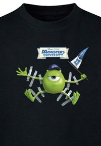 Sorte bomulds T-shirt med et grønt tegneseremonster med et øje, iført en blå kasket, omgivet af grå tape og holdende et blåt flag.