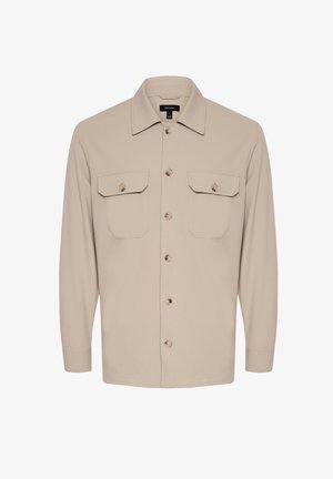 Cămașă bej deschis, cu butoni, fabricată dintr-un material moale; prezintă un guler, două buzunare pe piept și mâneci lungi cu manșete cu butoni.