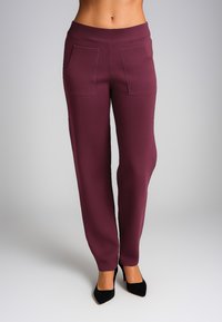 Pantaloni in jersey bordeaux con un ampio elastico in vita, due tasche frontali e una superficie liscia, abbinati a décolleté nere a punta.